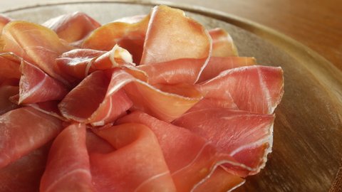 Cured raw ham, spinning. Slices of prosciutto crudo, Italian food. Pork dried ham. Antipasto, cold cuts. 4k video.