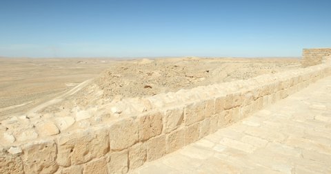 4K pan shot the Avdat Ruin in the Negev Desert in southern Israel, site of a ruined Nabataean city on a sunny day with a blue sky, stony pillars and walls, archaeology, adventure holidays, Middle East