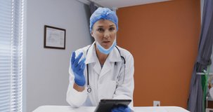 Caucasian female doctor at desk talking and gesturing during video call consultation. telemedicine, online healthcare services during quarantine lockdown.