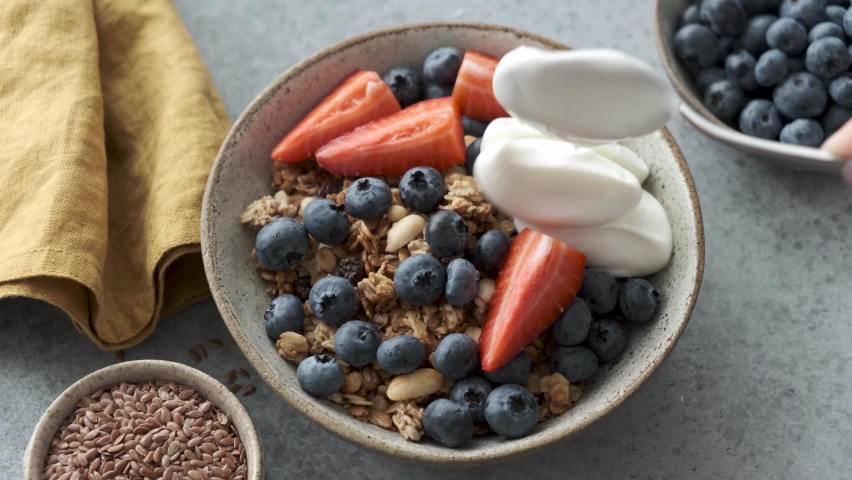 Granola bowl with berries and greek yogurt. Adding greek yogurt to homemade granola for healthy breakfast | Shutterstock HD Video #1071574045
