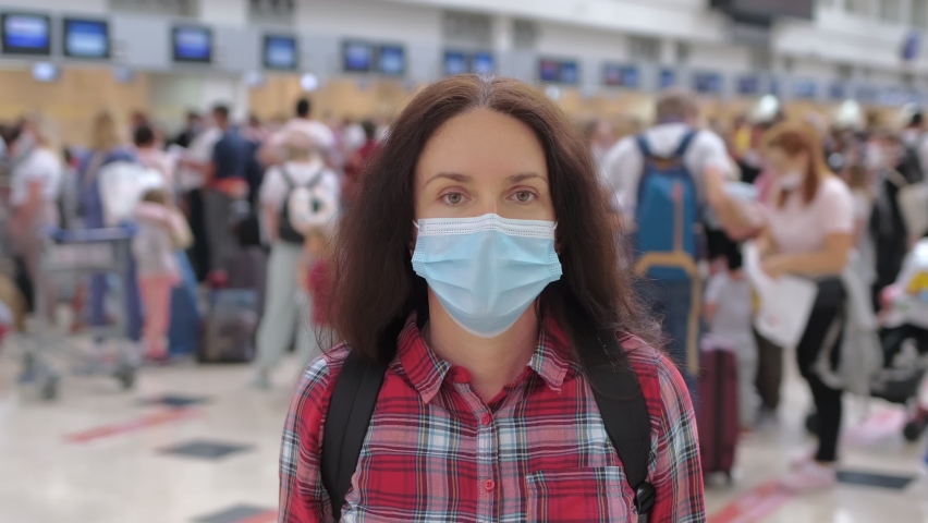 Traveler tourist woman in airport check-in for flight boarding plane wearing in face mask. Virus outbreak Coronavirus COVID-19 quarantine pandemic. Safe travel tourism checking flight board airline