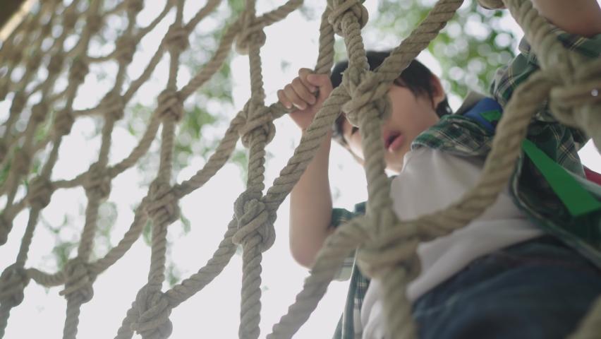 Focus Rope mesh, Slow-motion.Asian boys learn to climb a rope wall To enhance the development of the body Was in the park on holidays with close supervision by parents. Royalty-Free Stock Footage #1071590158