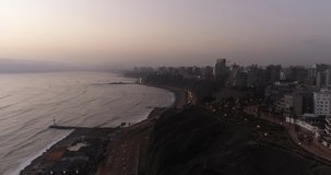 Aerial video made with drone over Lima city coast cliff during cloudy day in the afternoon. Highway at night know as 