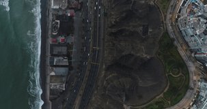 Aerial video made with drone over Lima city coast cliff during cloudy day in the afternoon. Highway at night know as 
