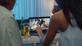 Young Asia female drinking beer having fun happy moment night party event online celebration via video call in living room at house at night. Social distancing, quarantine for coronavirus prevention.