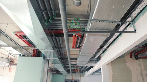 Pipes and ventilation on the ceiling of the building corridor. Switching of ventilation shafts and water pipes and heating of the building
