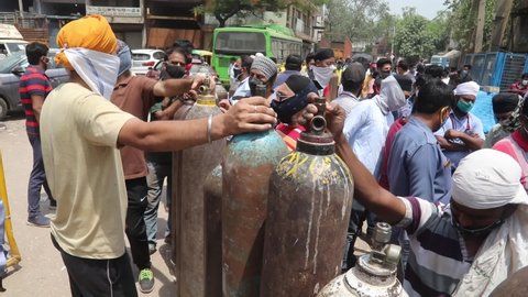 NEW DELHI, INDIA - APRIL 27 2021: People stands in queue for refilling empty oxygen cylinders outside refilling center. India faces the huge oxygen crisis during Covid-19 pandemic