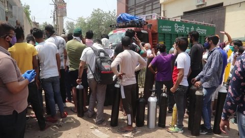 NEW DELHI, INDIA - APRIL 27 2021: People stands in queue for refilling empty oxygen cylinders outside refilling center. India faces the huge oxygen crisis during Covid-19 pandemic