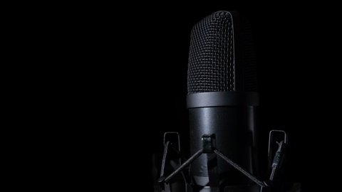 A close-up of a rotating microphone against a black background. Copy space.