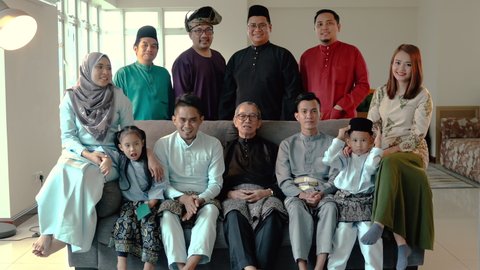 Eid Mubarak celebration moment, big family photo at the sofa wearing traditional cloth. Happy asian family