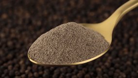 ground black pepper in golden spoon and peppercorn on background. Flavorful and aromatic black pepper. 4K UHD video