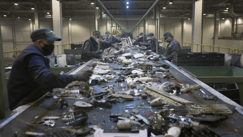 Male workers sort and recycle electronic waste and scrap metal. Plastic and polymer household waste is transported on a conveyor belt in the factory. Ecology of the planet. | Shutterstock HD Video #1071634042