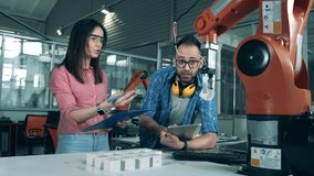 Robotic arm moves cubes while engineers watch it. - Powered by Shutterstock - Get 15% off with code: PIKWIZARD15