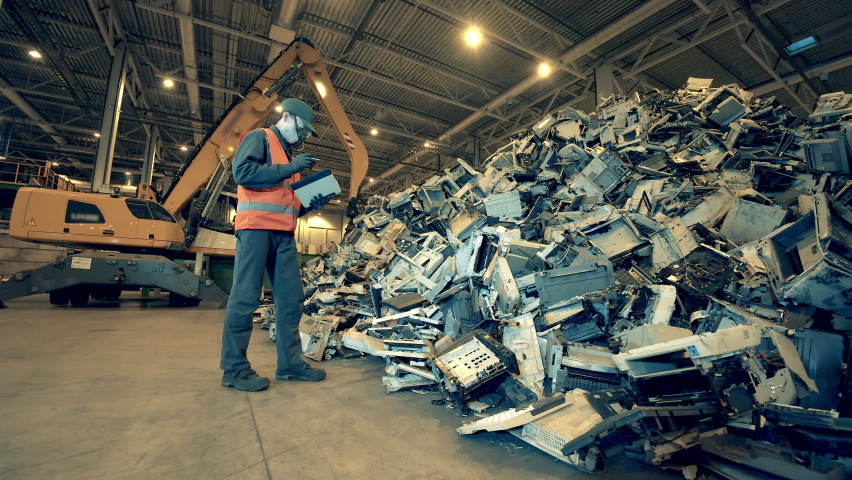 Male worker is inspecting fractions of thrown-out computers. Garbage, trash, waste recycling factory. Royalty-Free Stock Footage #1071634609