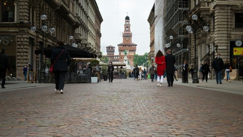 April 28, 2021, Milan,Italy: Perspective of the famous Via Dante (meaning: "Dante's Street") with pedestrians walking in the city. On the background the Castello Sforzesco (meaning: Sforza's Castle).