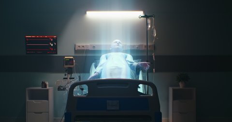 Medical practitioner turning off life support machine then soul of dead man leaving body in dark ward of contemporary clinic
