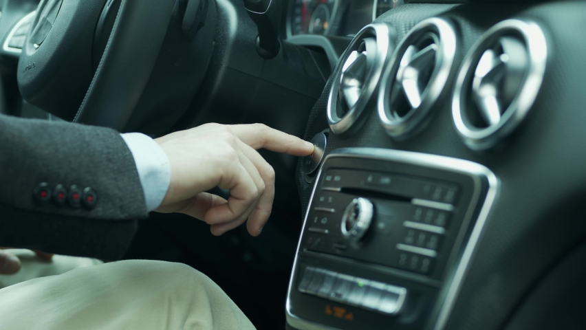 The man turns on the car. Leave with the car. Press the power button. interior, car, start