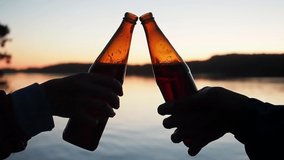 Group of friends clink brown glass beer bottles against the sky and sunset, the bottom corner of the camera. The soft rays of the sun shine through the glass of a bottle - Powered by Shutterstock - Get 15% off with code: PIKWIZARD15