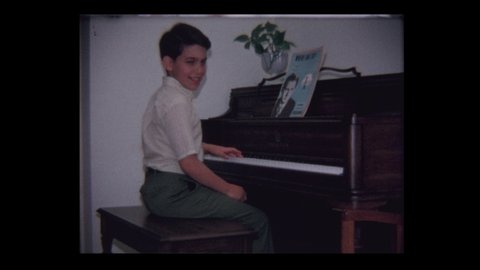 Baltimore, MD, USA, 1971: Proud young boy plays piano and bows