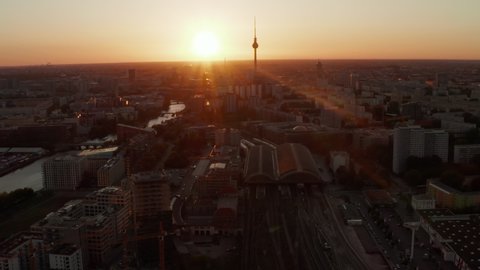 AERIAL: Flight over Berlin, Germany at beautiful Sunset, Sunlight and view on Alexanderplatz TV Tower and Ostbahnhof, Sunflairs