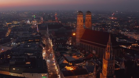The Famous Frauenkirche Church Cathedral in Munich at Night, Aerial Dolly forward approaching two towers of beautiful old building, Scenic City Lights glowing