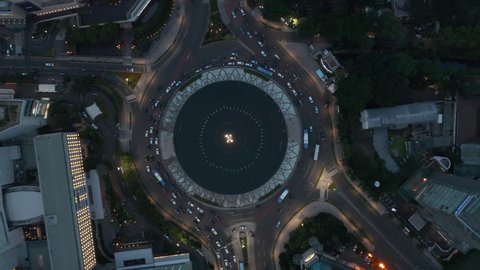 Aerial Birds Eye Overhead Top Down rotating View of busy city traffic in the Selamat Datang Monument roundabout at night