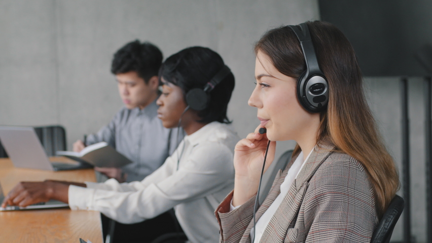Serious caucasian female call center agent wear wireless headset using laptop looking at screen consulting customer with online problem make video call in office, focused woman work in support service Royalty-Free Stock Footage #1071696778