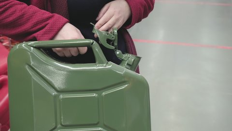 Woman in the parking lot store chooses for buys a big iron canister under fuel. Concept of women independence, feminism, gender equality. Hands close up shot