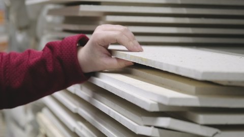 Woman buys fiberboard for wall coverings in a building materials store. Hands close up shot. Concept of women independence, feminism, gender equality, repair and construction