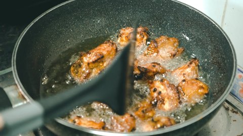 Fried pork bones in a pan on the gas stove in the kitchen