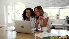 Mixed race female friends working in kitchen engaging in video call on laptop screen
