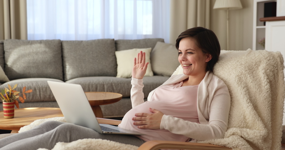 Pregnant woman rest on armchair talk on video conference with family, receiving remote consultation using video call app on laptop. Obstetrician gynaecologist give medical care online counsel concept Royalty-Free Stock Footage #1071713875