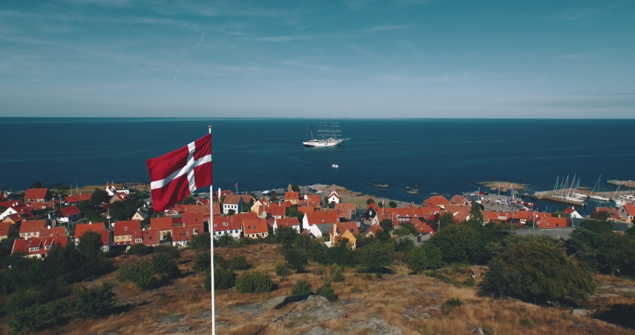Denmark flag flyby aerial view sailboat at coastline harbour ocean summer 4k