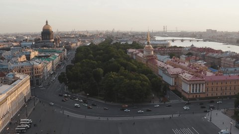  Aerial footage of Palace Square and Alexander Column at sunset, a gold dome of St. Isaac's Cathedral, the Admiralty building, little people walks, car traffic
