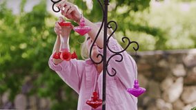 Static view of woman hanging up hummingbird feeders on a metal holder.