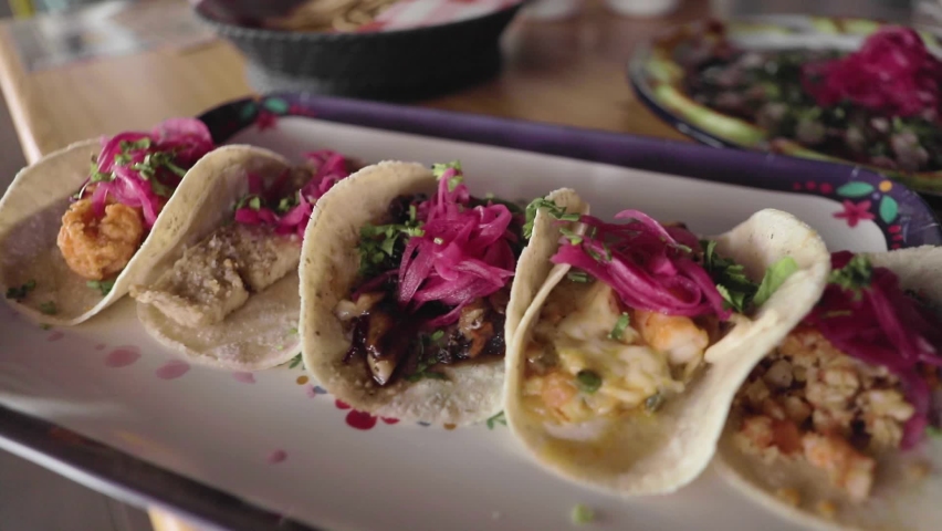 A handheld shot of a sampler platter of shrimp and fish tacos in a traditional sinaloan mexican restaurant.