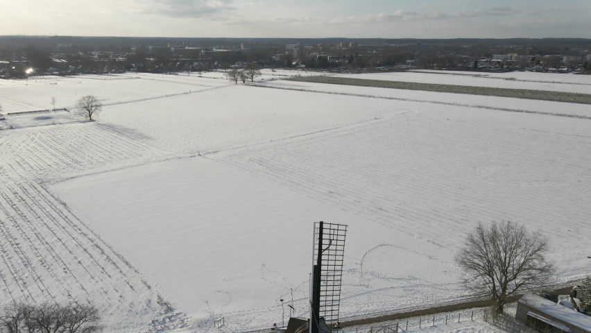 jib down of traditional dutch windmill standing in beautiful snow covered meadow