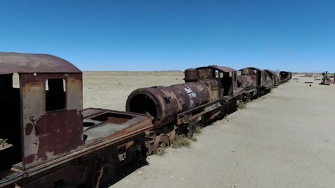 Amazing landscape, aerial shot general view. Deposit of metals and machines in the desert. Amazing desert landscape. Heavenly scenery, clear skies, old trains. South America, train graveyard 4k drone