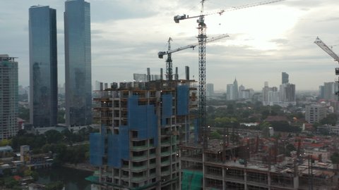Close up aerial view of crane lowering an object on the roof of the skyscraper under construction in Jakarta, Indonesia