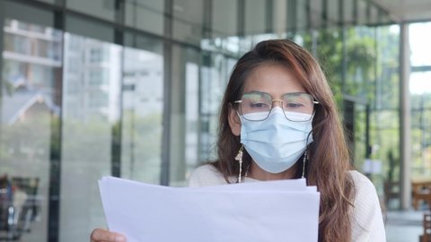 senior manager, adult woman wearing facemask working outdoor check business paper and talking wall glass background. Teacher Female wearing eyeglasses talking with student.  