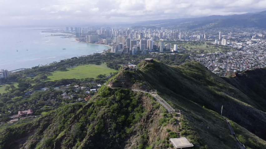 Aerial above peak of Diamond Head mountain with Honolulu city Downtown skyscrapers on the horizon, Hawaii Royalty-Free Stock Footage #1071748885