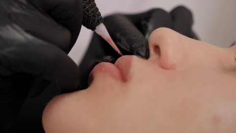 Close-up of the process of applying permanent makeup to the lips.