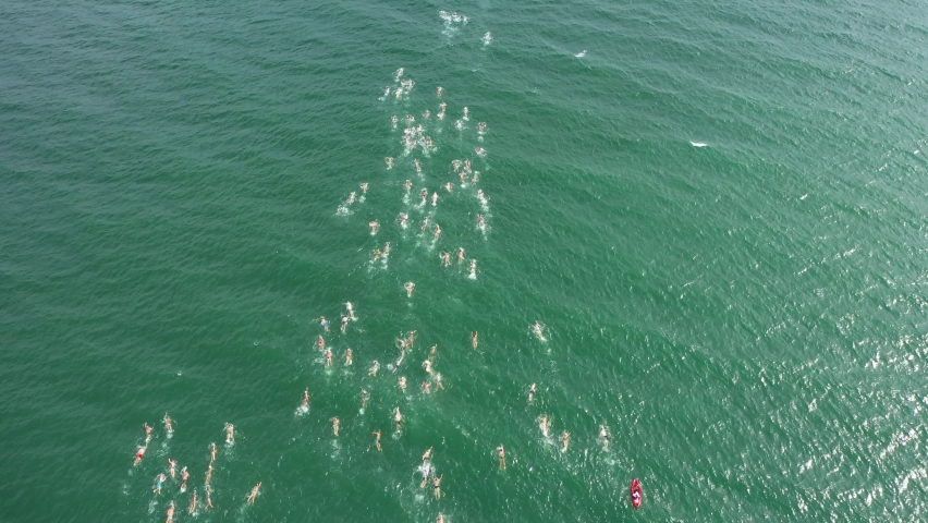 Aerial Drone Shot 4K of Triathlon Swimming Race. Ironman Competition. Traditional swimming marathon in Varna, Bulgaria. A huge group of people invades the water. Start swimming in the sea or ocean. Royalty-Free Stock Footage #1071756949