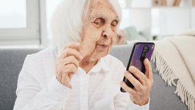 Elderly woman making video call with smartphone and smiling during converstation
