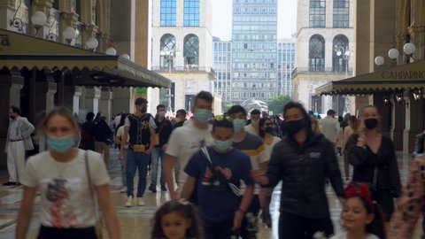 People in protective masks. tourists and local residents of the city in the gallery Vittorio Emanuele 2. Crowds of people. Shopping. Opening borders in Europe. Epidemic. Milan, Italy - May 2021: 