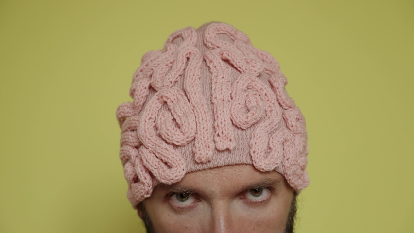 Close up of male eyes and head in pink brain hat. Thinking creative process. Man scratching on yellow background, moving, looks to the sides. Ready to work, brainstorm advertising agency fashion style Royalty-Free Stock Footage #1071766081