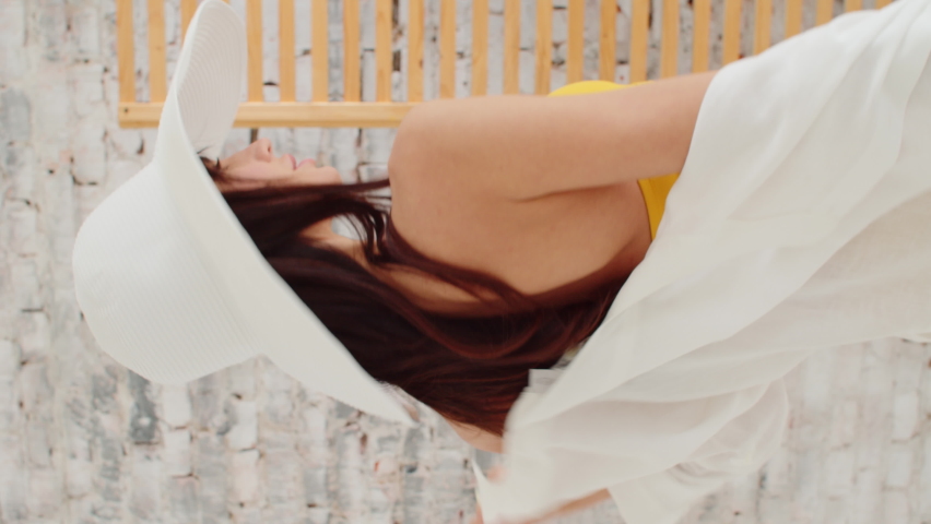 Young girl in a yellow swimsuit. Female model posing in split pareo swimsuit and hat. Attractive woman with hat in the studio.