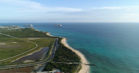 COCKBURN TOWN, TURK AND CAICOS ISLAND, SEPTEMBER 2018: Flying above the road by the beach and coral reefs with cruise ships on horizon