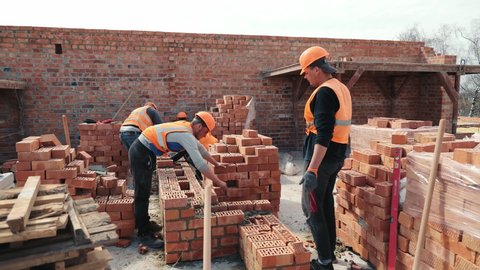 Builders building a brick wall. Construction work on construction. The masters lay bricks and build the wall of the house.