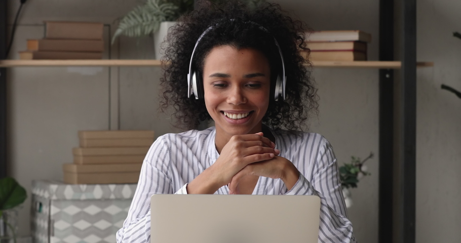 African businesswoman sit at desk wear headphones using video conferencing app on laptop talk to client remotely, solve business distantly. Videocall event, virtual meeting, modern tech usage concept Royalty-Free Stock Footage #1071788545